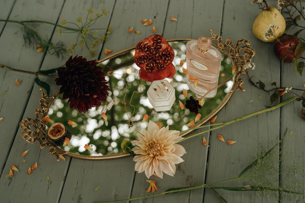 Styled wedding details arranged with florals, fruit, perfume, and jewelry on a vintage mirrored tray for an editorial-inspired New England wedding aesthetic.