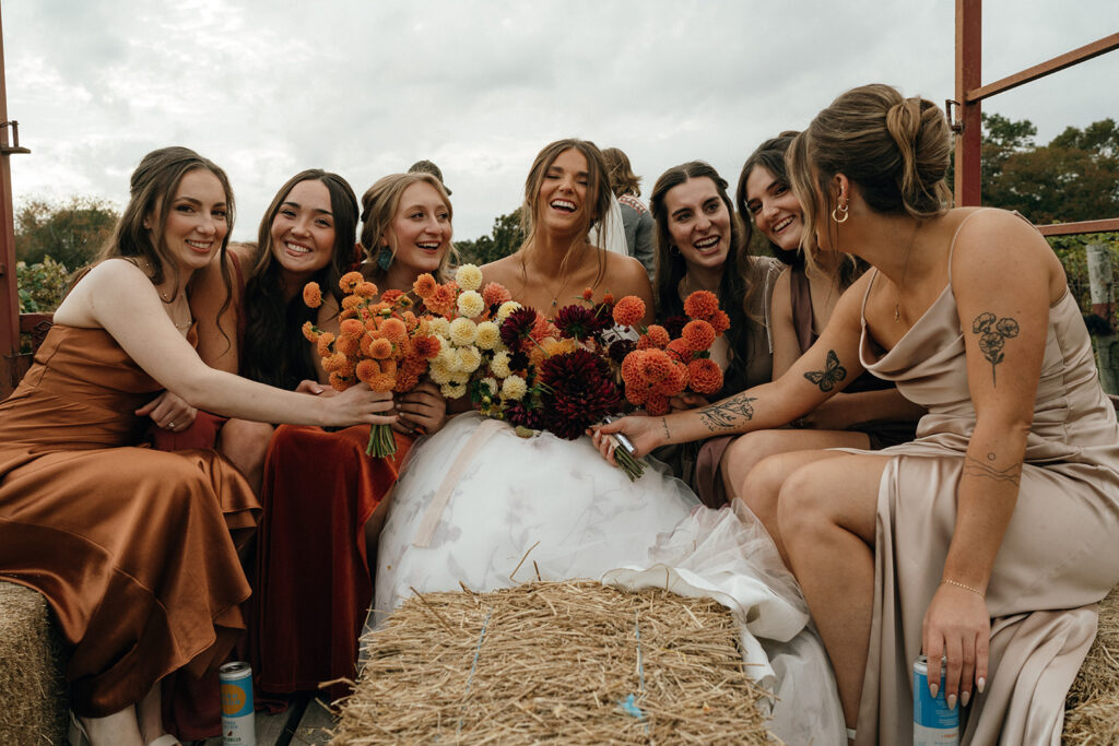 Bride laughing with bridesmaids holding colorful fall bouquets at a New England wedding destination