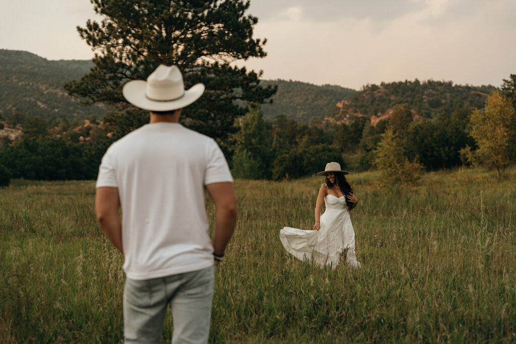 A couple walks toward each other through a mountain meadow in wedding attire, reflecting the beauty of rural New England wedding locations.