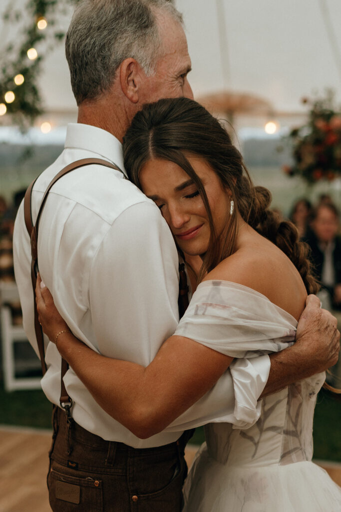 Bride resting against an older family member during a tender reception embrace, a quiet story captured through documentary wedding photography in New England.