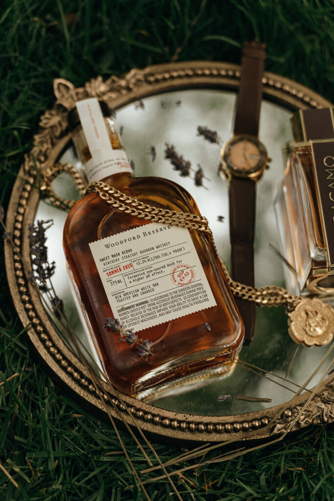 Styled wedding details arranged on a vintage tray with whiskey, jewelry, and coastal-inspired textures often seen at elevated New England beach wedding venues.