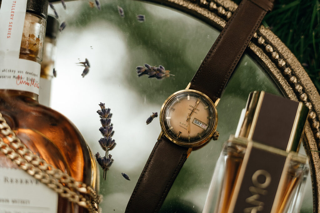 A close-up of a vintage watch styled with lavender rests on a reflective surface, adding a refined detail that complements the timeless aesthetic of luxury New England castle wedding celebrations.