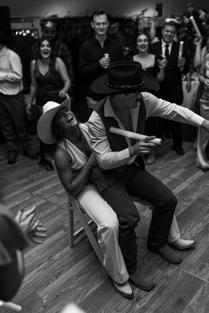 Wedding guests cheering as the couple dances beneath a cowboy hat, photographed with the spontaneity of a candid wedding photographer in New England.