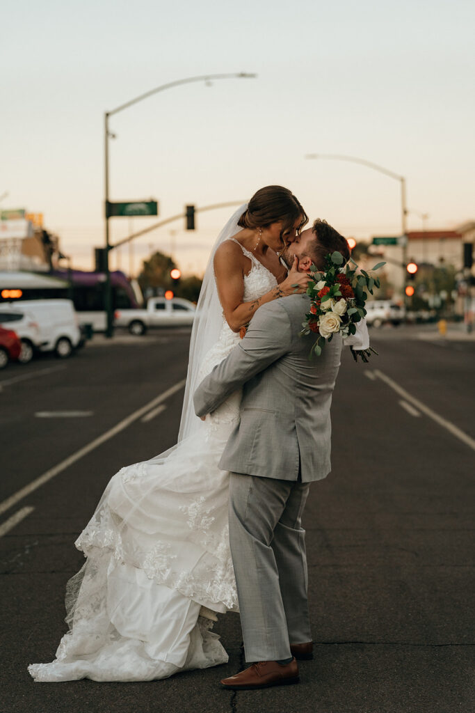 Eloping in New England | Aisha Lee Photography Cinematic Wedding Photographer | Bride in white gown and groom in gray suit kiss passionately in the middle of an empty street at sunset, conveying romance and joy.
