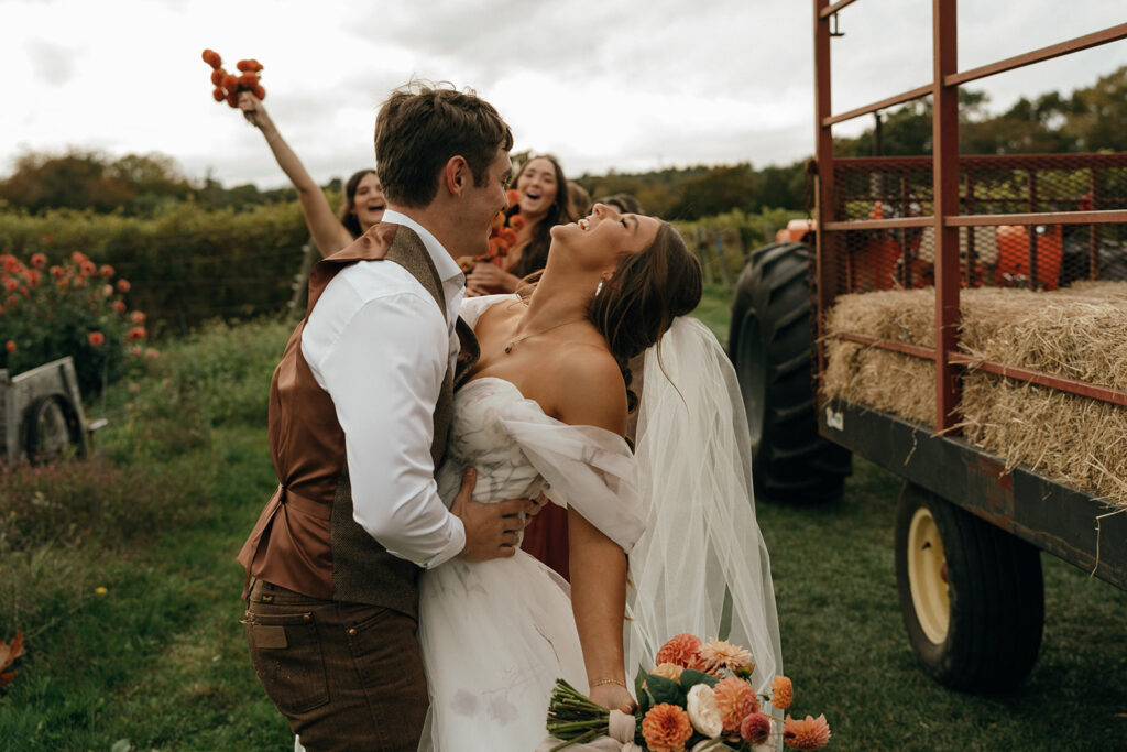 Bride leaning back in laughter while the groom holds her during an outdoor celebration, a joyful moment preserved by an experienced wedding photographer in New England.