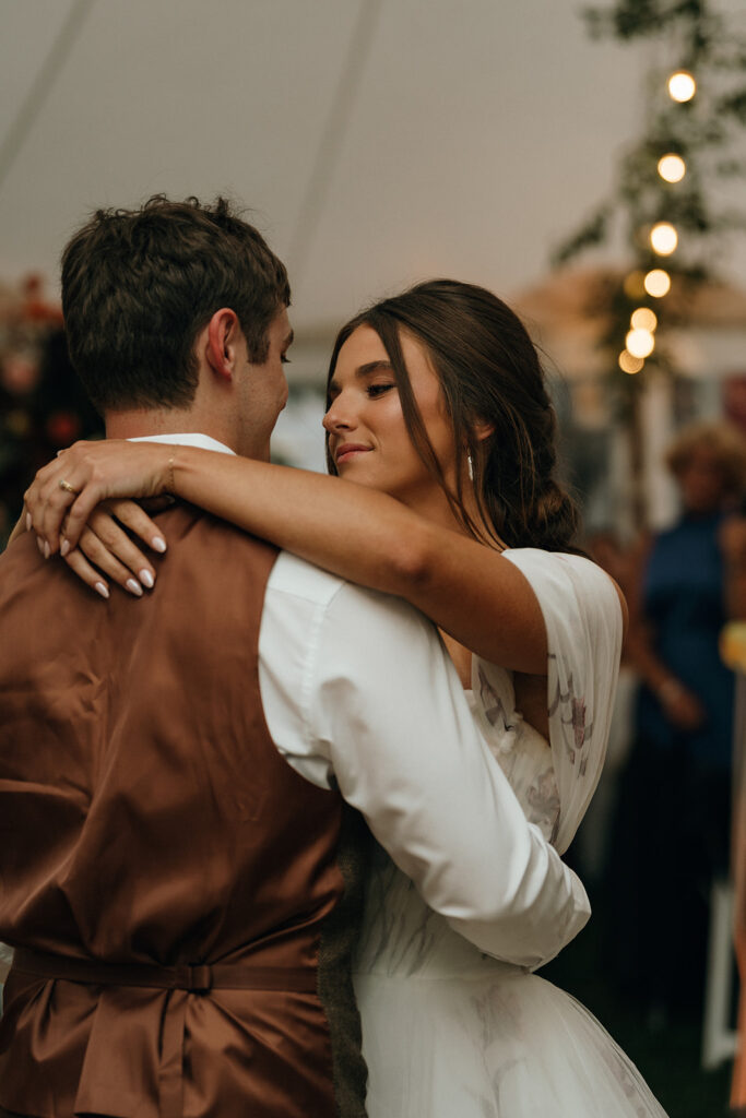 Cinematic Wedding Photographer Rhode Island | Aisha Lee Photography Cinematic Wedding Photographer | A bride and groom share a tender dance at their wedding. She smiles softly, closing her eyes. Warm lighting and blurred guests
