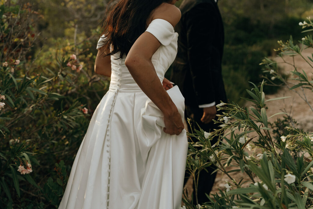 Close-up of a structured satin wedding gown with covered buttons and elegant draping captured during a refined New England wedding celebration.