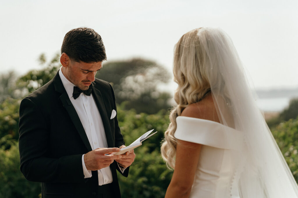 Groom reading vows or a letter during a quiet outdoor ceremony moment, capturing the intimacy of New England elopements.